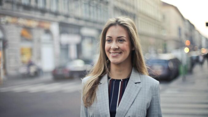 Confident businesswoman smiling outdoors in urban Budapest setting.