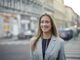 Confident businesswoman smiling outdoors in urban Budapest setting.