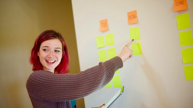 woman in gray sweater holding white and yellow sticky notes